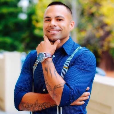 Portrait photograph of Cris Gomez smiling, wearing a blue shirt