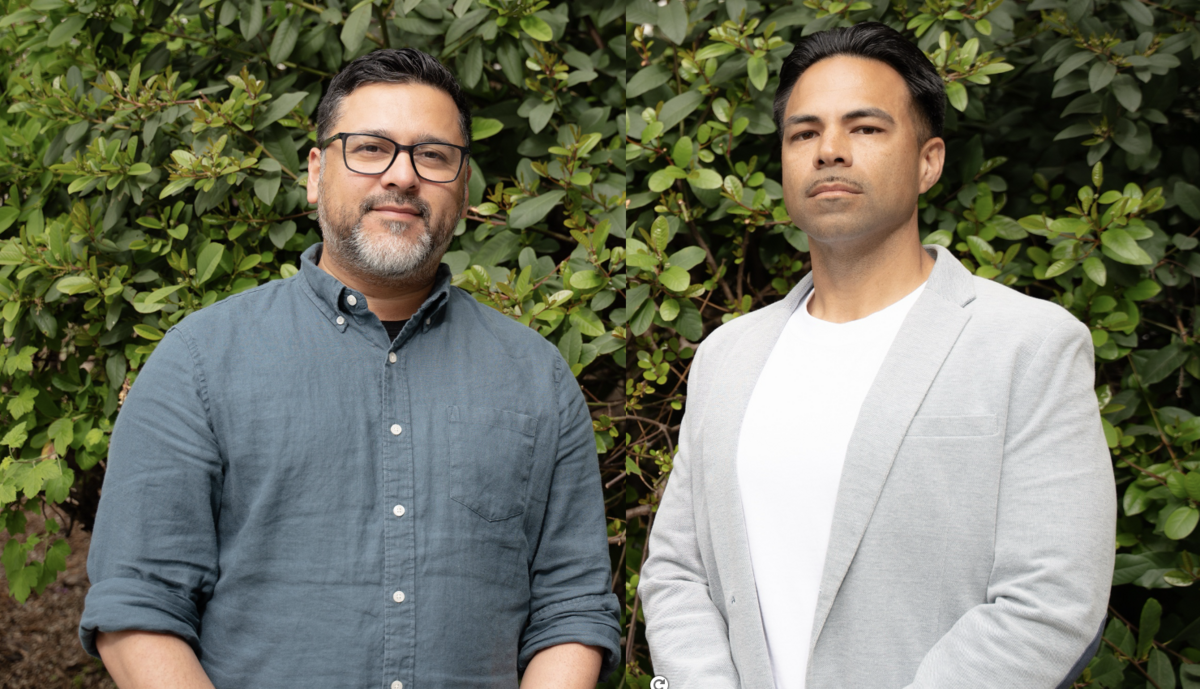 Two Reentry counselors standing side by side in front of a green tall bush